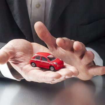 car insurance company root insurance man in suit holding red toy car in hand